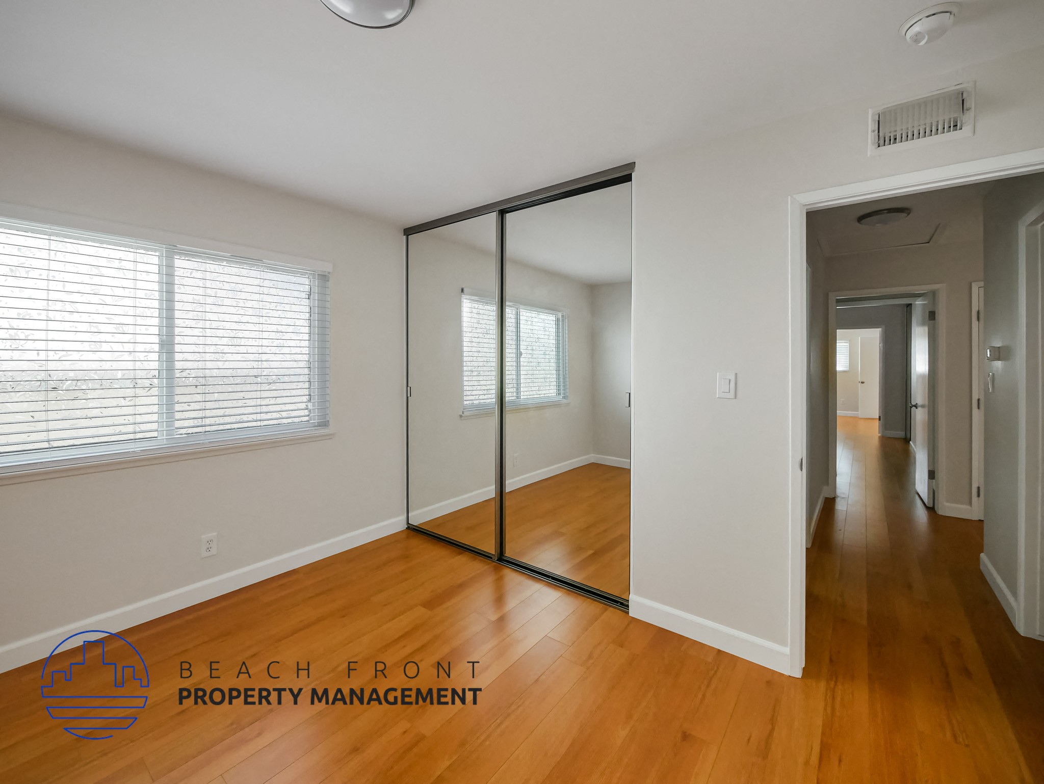A room with a sliding glass door and wooden floors.